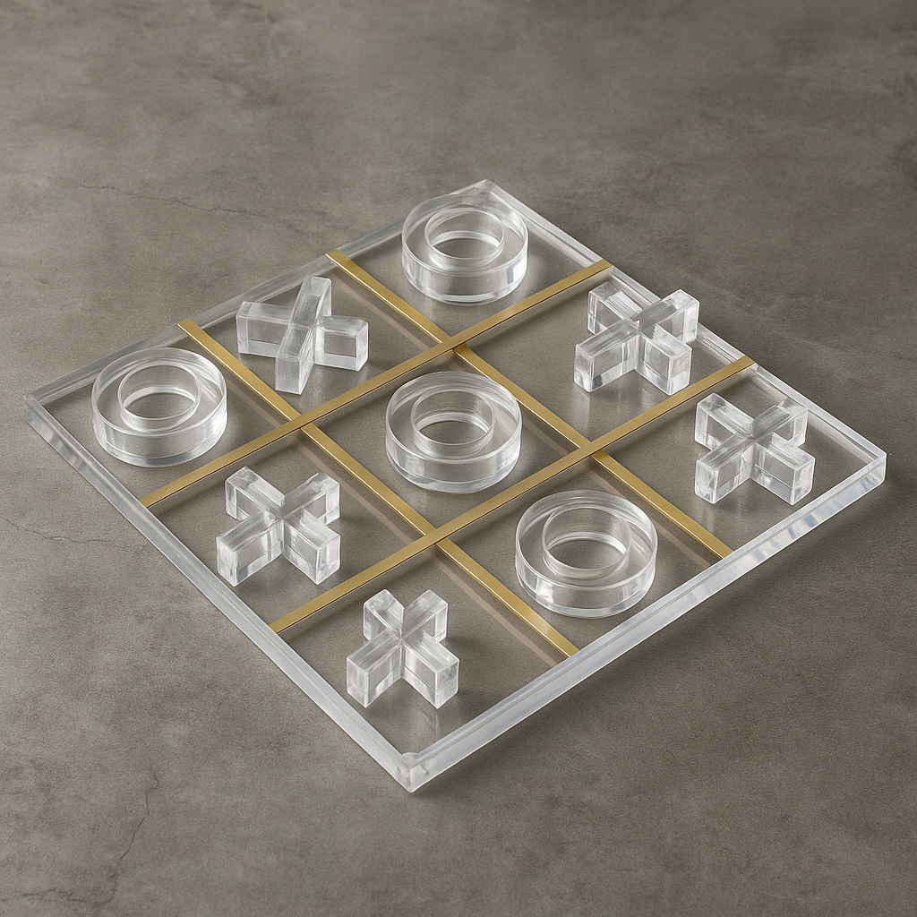 Angled view of lucite acrylic Tic Tac Toe board with gold grid and clear pieces on gray stone surface
