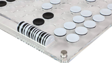 Black and white Othello game discs arranged on lucite board