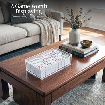Luxury acrylic Mahjong tile set in a clear lucite case displayed on a modern wooden coffee table in a styled living room